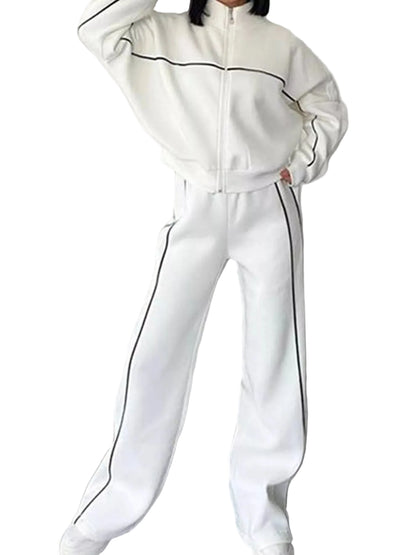 A person wearing a white zip-up track jacket and matching wide-leg sweatpants with thin black side piping, standing against a plain light wall.