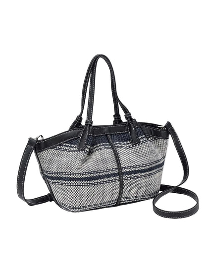 A structured tote bag featuring a black and white herringbone patterned body with solid black leather trim, double top handles, and an adjustable shoulder strap, shown against a plain light gray background.