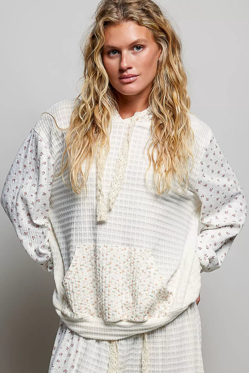 Woman wearing a white patterned blouse against a gray background