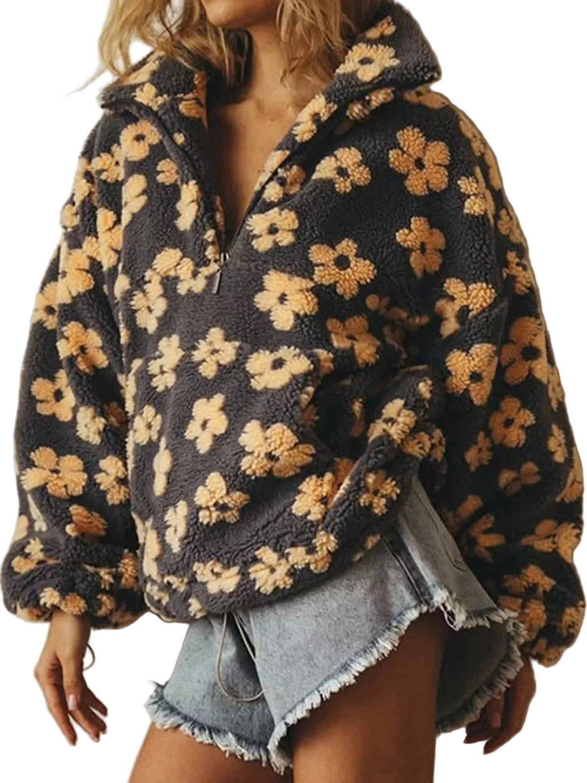 A woman wearing a dark charcoal gray fuzzy fleece pullover jacket with a tan and beige floral pattern, paired with frayed denim shorts.