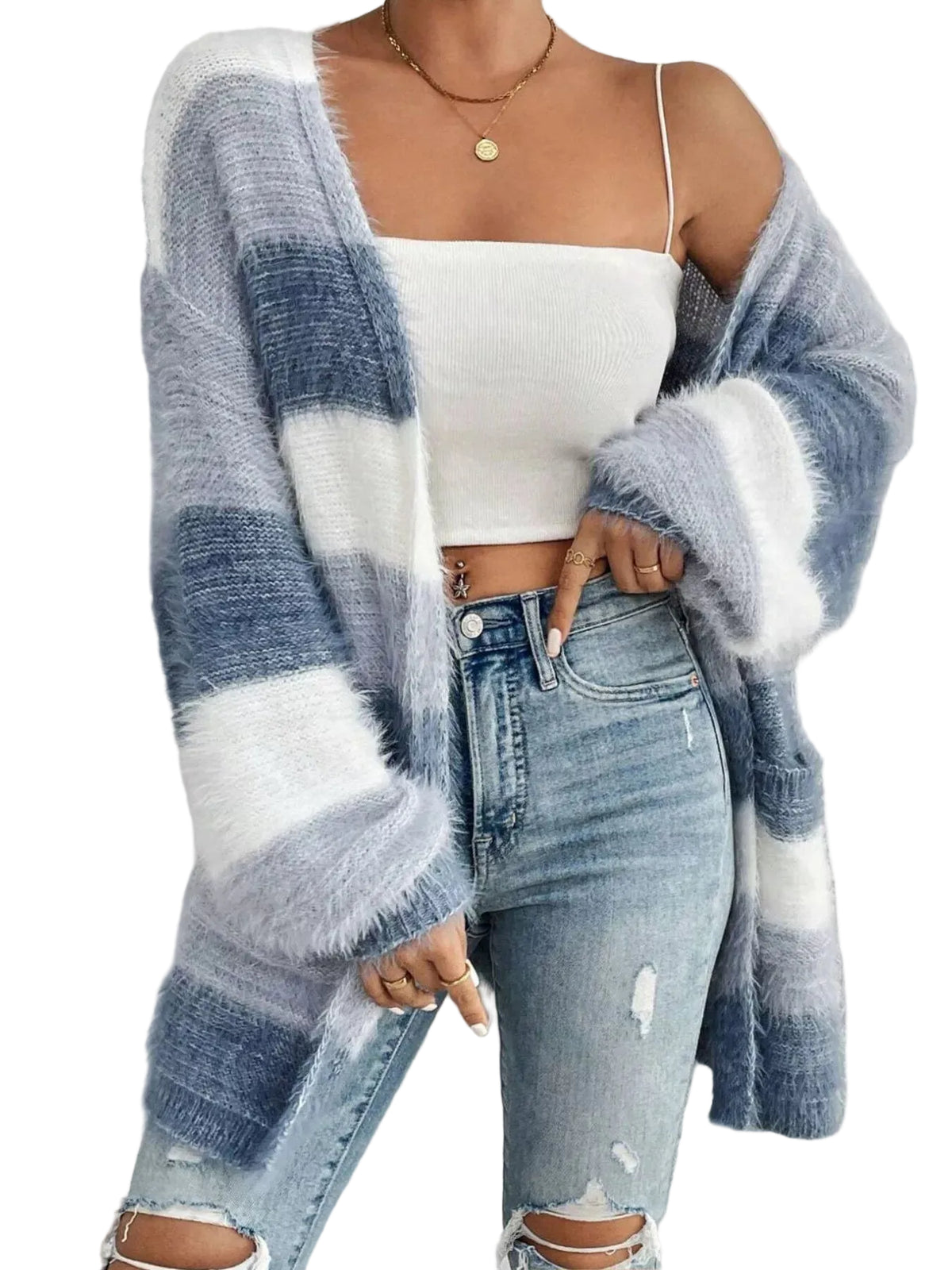 A person wearing a fuzzy oversized cardigan with wide blue, white, and light gray stripes over a white crop top and light-wash distressed jeans, standing against a textured light gray wall.