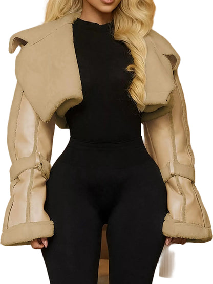 A woman wearing a beige shearling-style cropped jacket with wide flared sleeves over a black bodysuit, shown in an indoor setting with warm lighting.