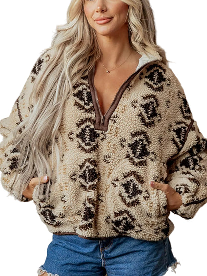 A woman wearing a beige sherpa fleece quarter-zip pullover with a brown and black leopard print pattern, paired with blue denim shorts, set against a rustic brick wall background.