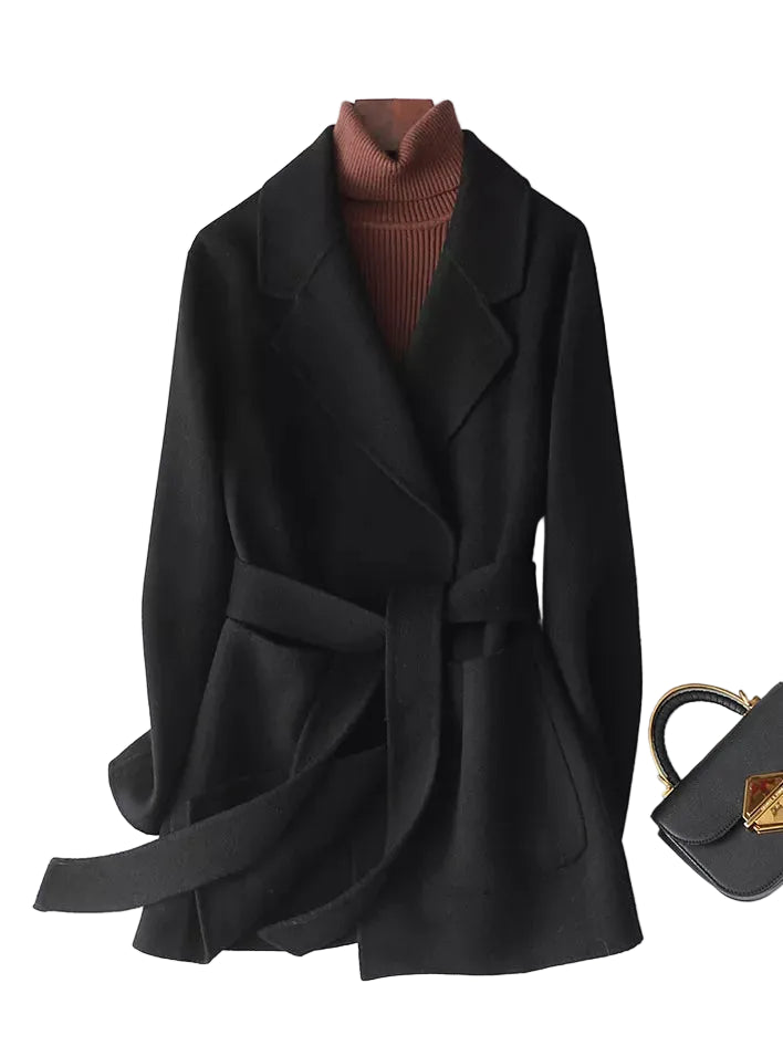 A black belted wrap coat styled over a brown ribbed turtleneck sweater, displayed on a white background next to a black handbag.
