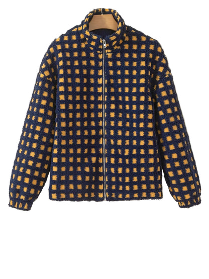 A fuzzy zip-up jacket with a blue and mustard yellow checkered pattern, hanging on a wooden hanger against a plain beige wall.