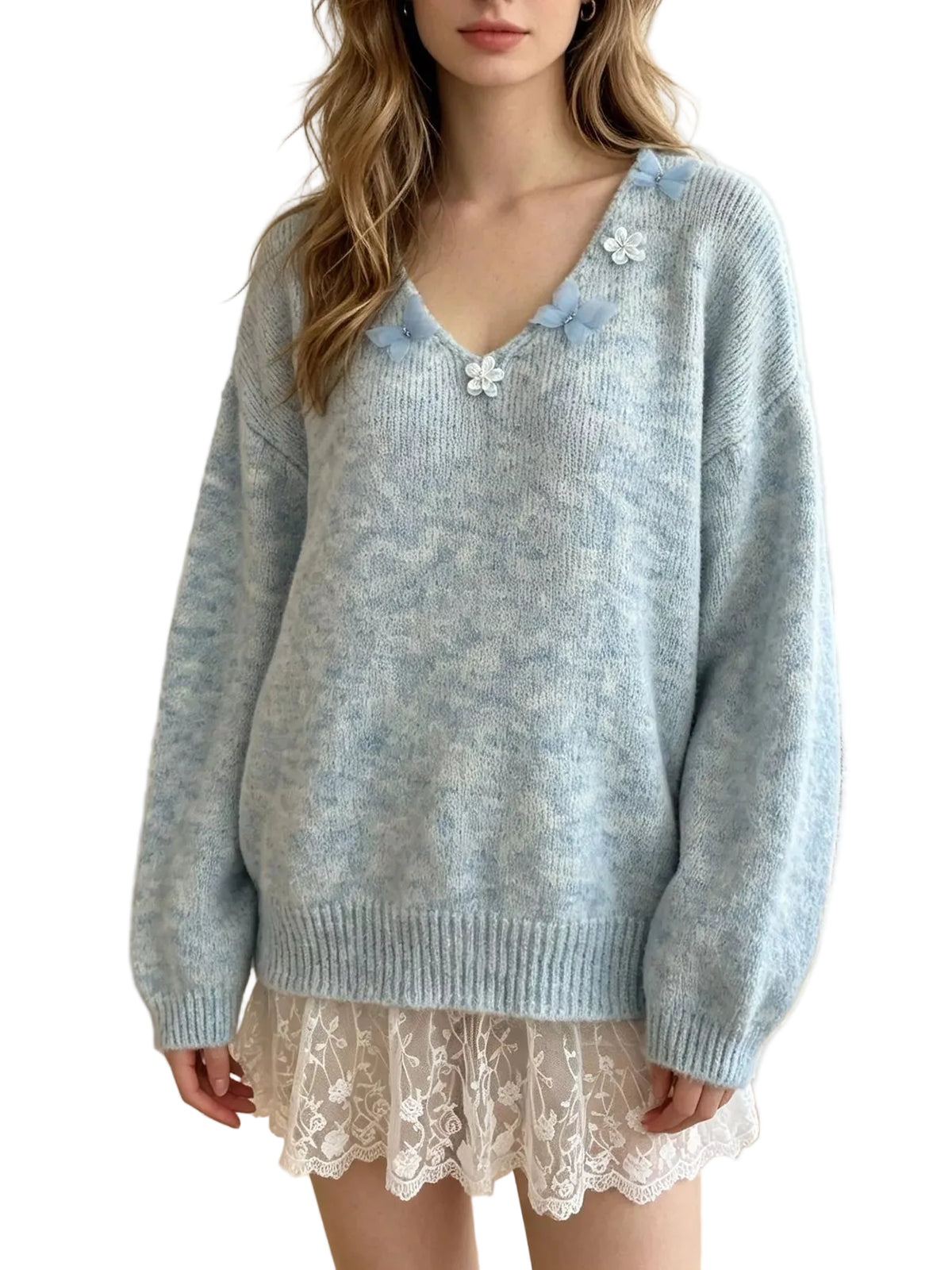 A woman wearing a light blue marled knit sweater with decorative white and blue flower embellishments on the neckline, paired with a white lace skirt in a bright indoor room.