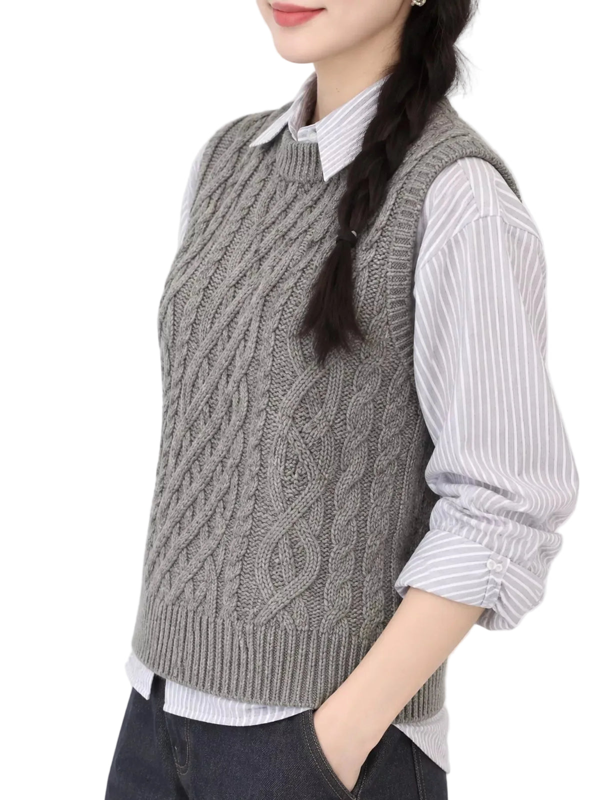 A woman wearing a gray cable-knit sweater vest over a white and gray striped button-down shirt, paired with dark jeans, shown from the chest down against a plain white background.