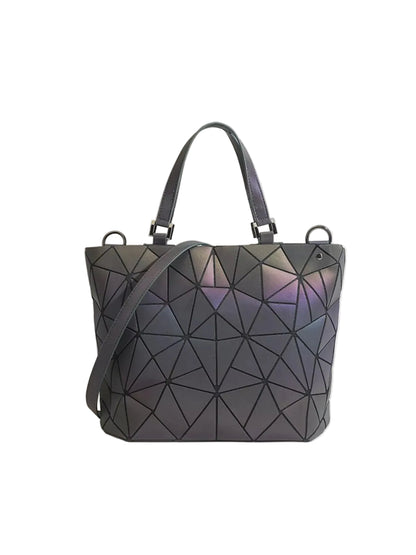 A geometric, faceted tote bag with a dark gray and black finish, featuring an iridescent purple and pink sheen under light, complete with dual top handles and a shoulder strap, set against a solid light beige background.