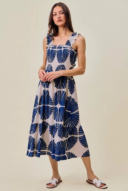 Woman wearing a sleeveless dress with a blue leaf pattern on a beige background