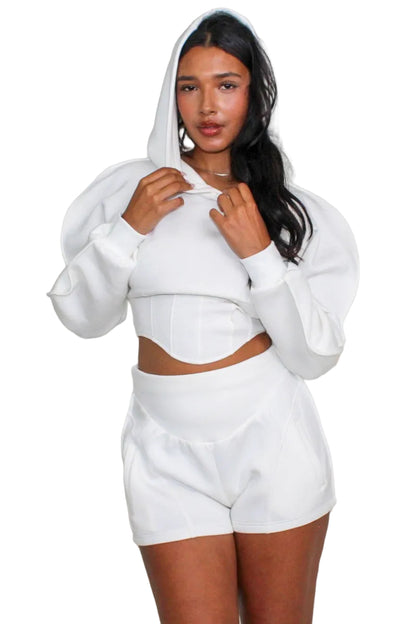 Person wearing a white hoodie and shorts set on a plain background