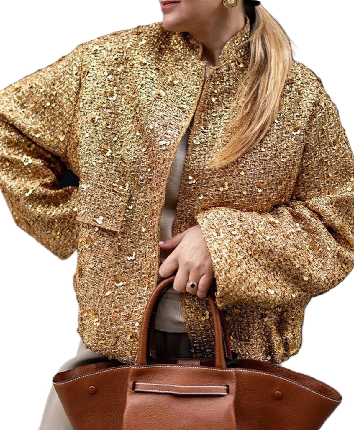 A woman wearing a gold sequined jacket and holding a brown leather handbag against a dark background.