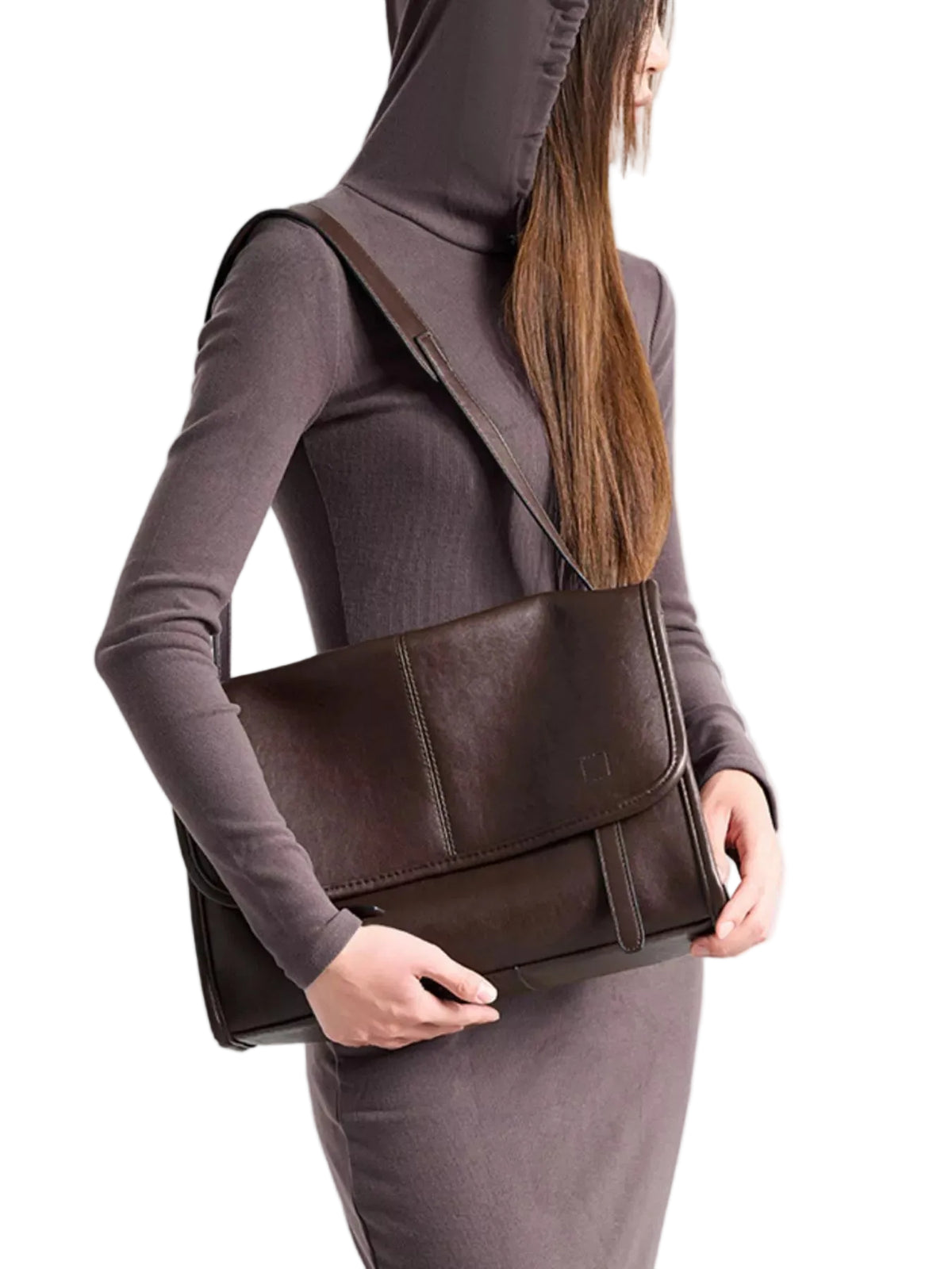 A woman wearing a dark brown long-sleeve dress carries a matching dark brown leather messenger bag over her shoulder against a light gray studio background.