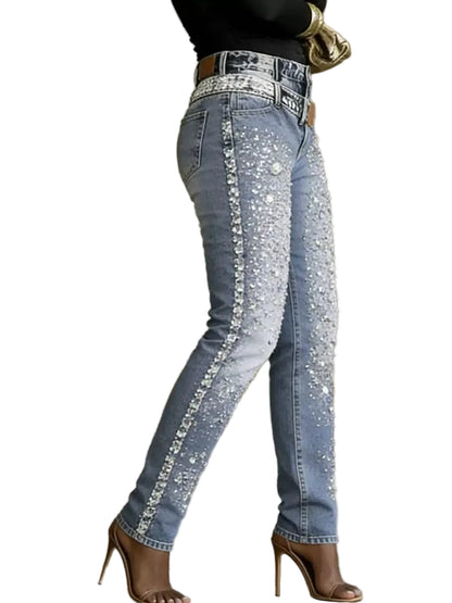 Light-wash blue jeans with extensive silver rhinestone embellishments down the outer seams, shown on a model wearing brown high-heeled sandals.