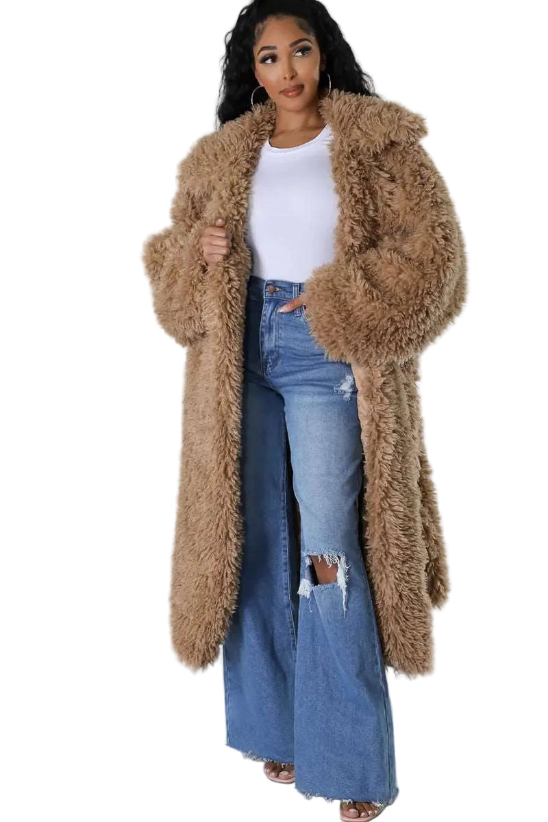 Woman wearing a long brown fur coat over a white top and blue jeans on a white background