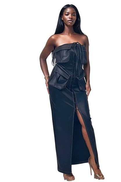 Woman wearing a dark blue strapless dress with a slit, standing against a white background.