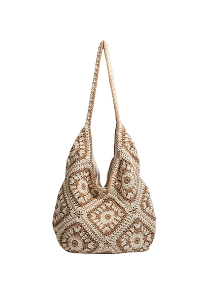 A crocheted shoulder bag with a geometric pattern in beige and brown, featuring a long matching crocheted strap, set against a light gray background.
