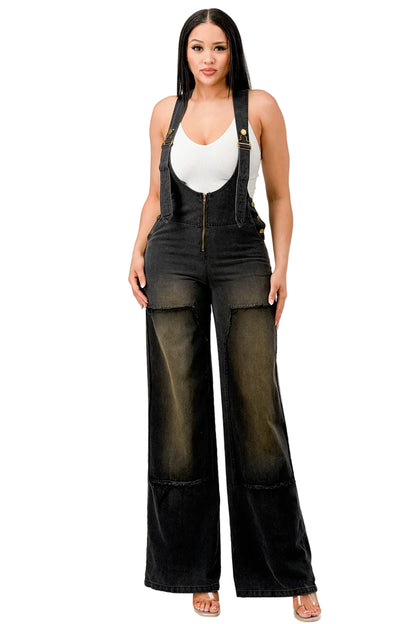 Woman wearing black denim overalls and a brown cowboy hat on a white background