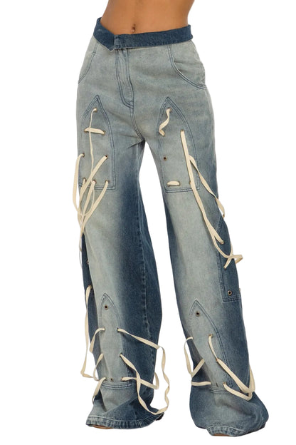 Wide-leg blue denim jeans with cream-colored lace-up details running down the front of the legs, shown on a model against a light gray background.