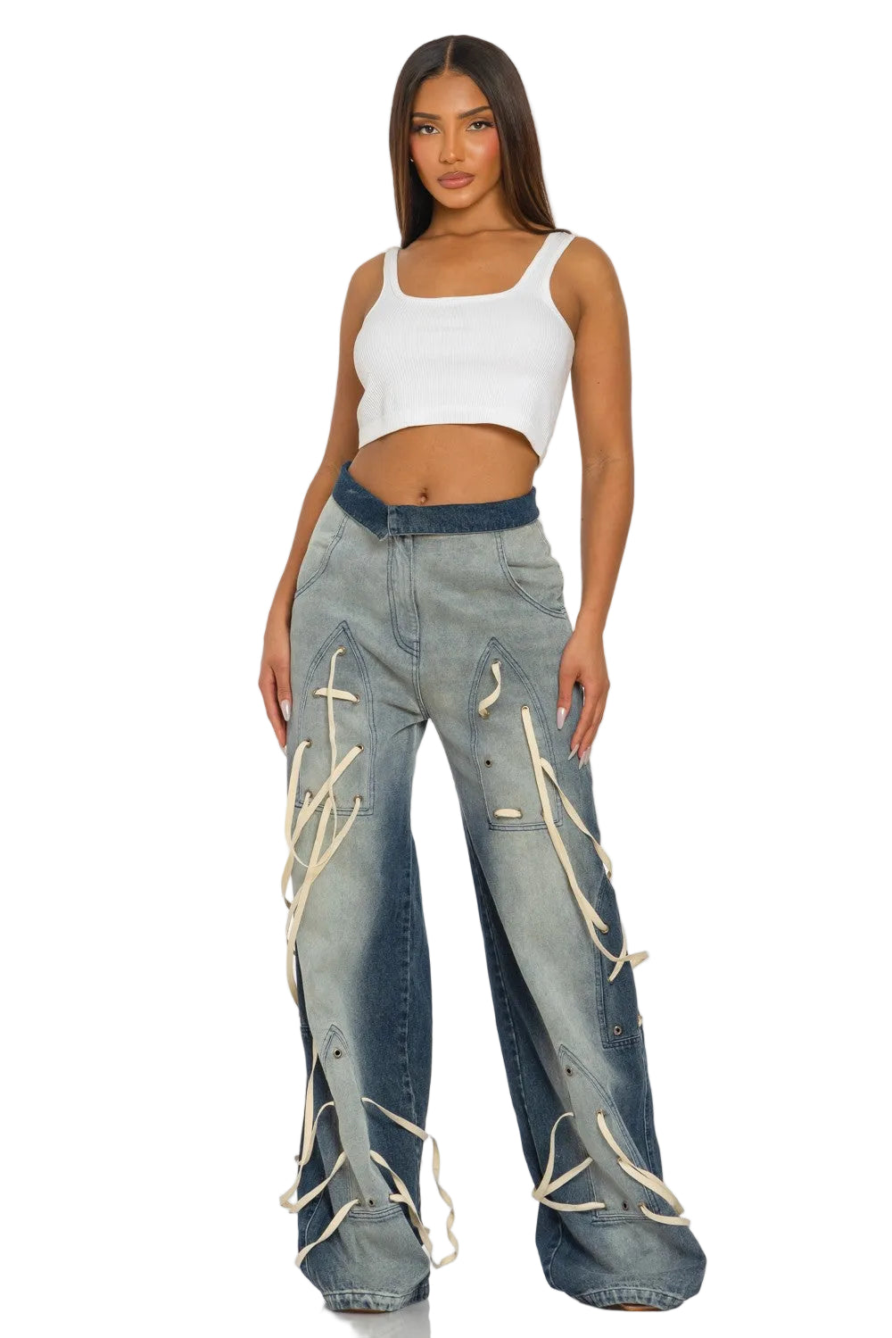 A model wearing a white ribbed crop top and wide-leg light-wash jeans with cream lace-up details, standing against a light gray studio background.