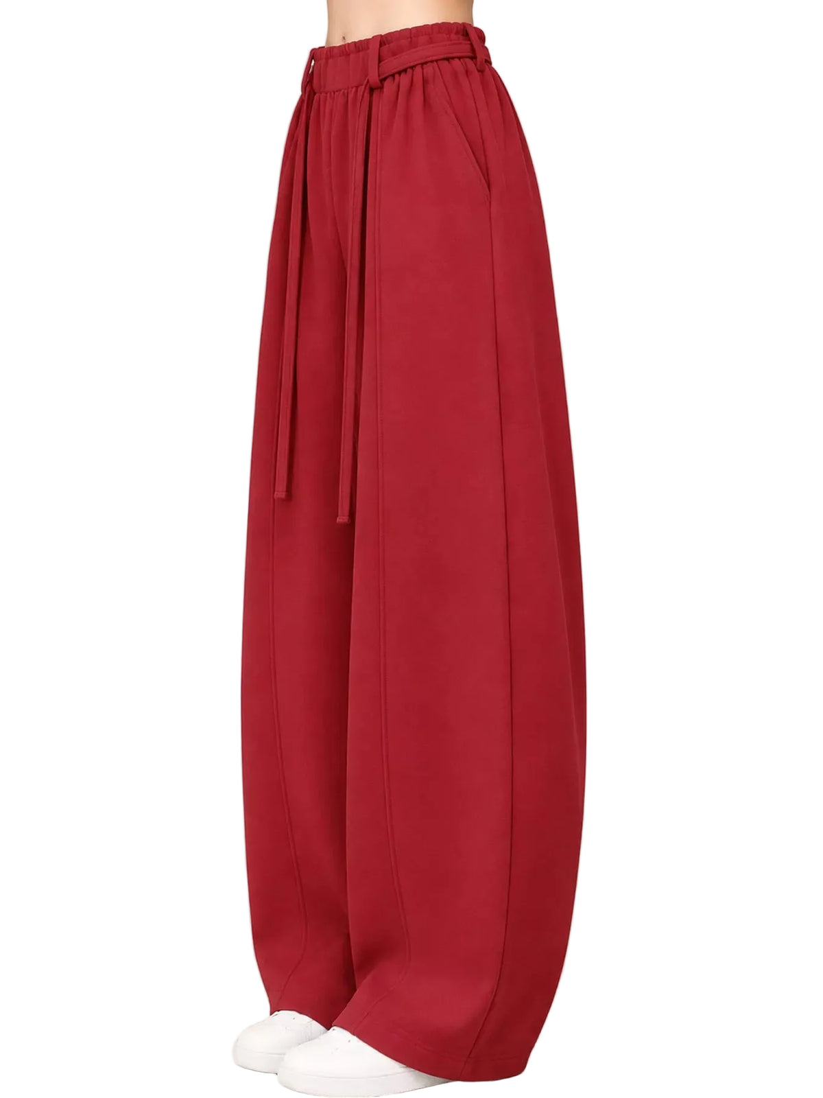 A pair of wide-leg, balloon-style pants in a deep red or burgundy color, featuring an elastic waistband with a matching tie belt, shown on a model from the waist down against a light beige studio background.
