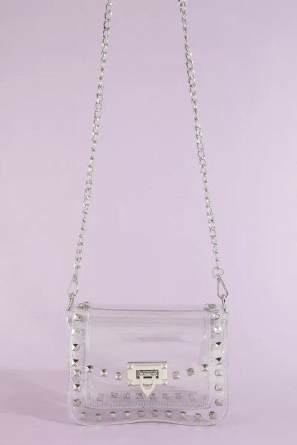 Clear handbag with silver studs and chain strap on a light purple background