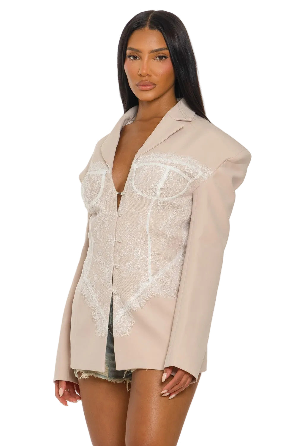 Woman wearing a beige oversized shirt with lace detailing on a white background