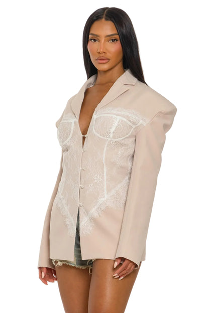 Woman wearing a beige oversized shirt with lace detailing on a white background