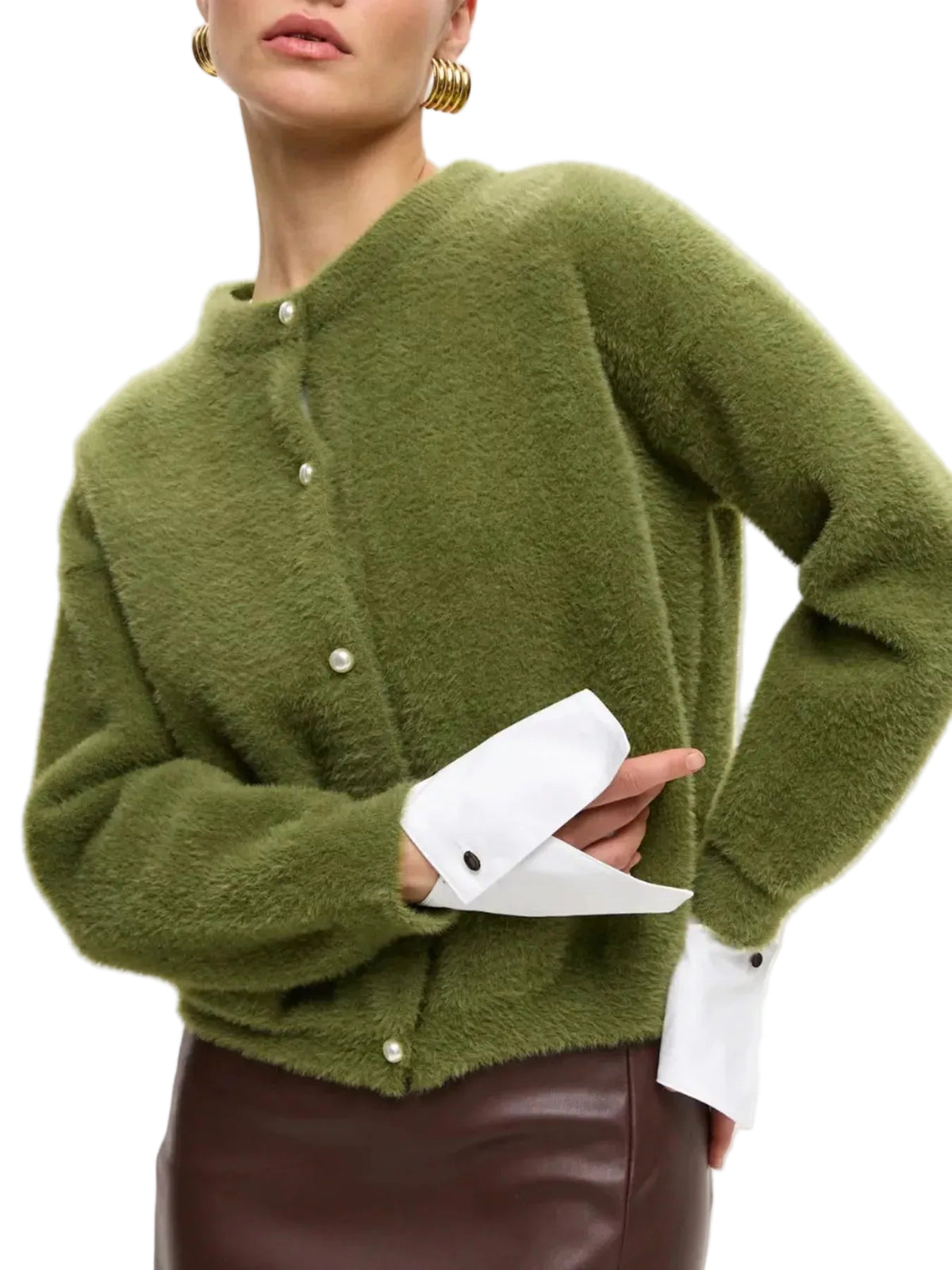 A close-up of a model wearing a fuzzy olive green cardigan with white shirt cuffs and a brown leather skirt against a plain white background.