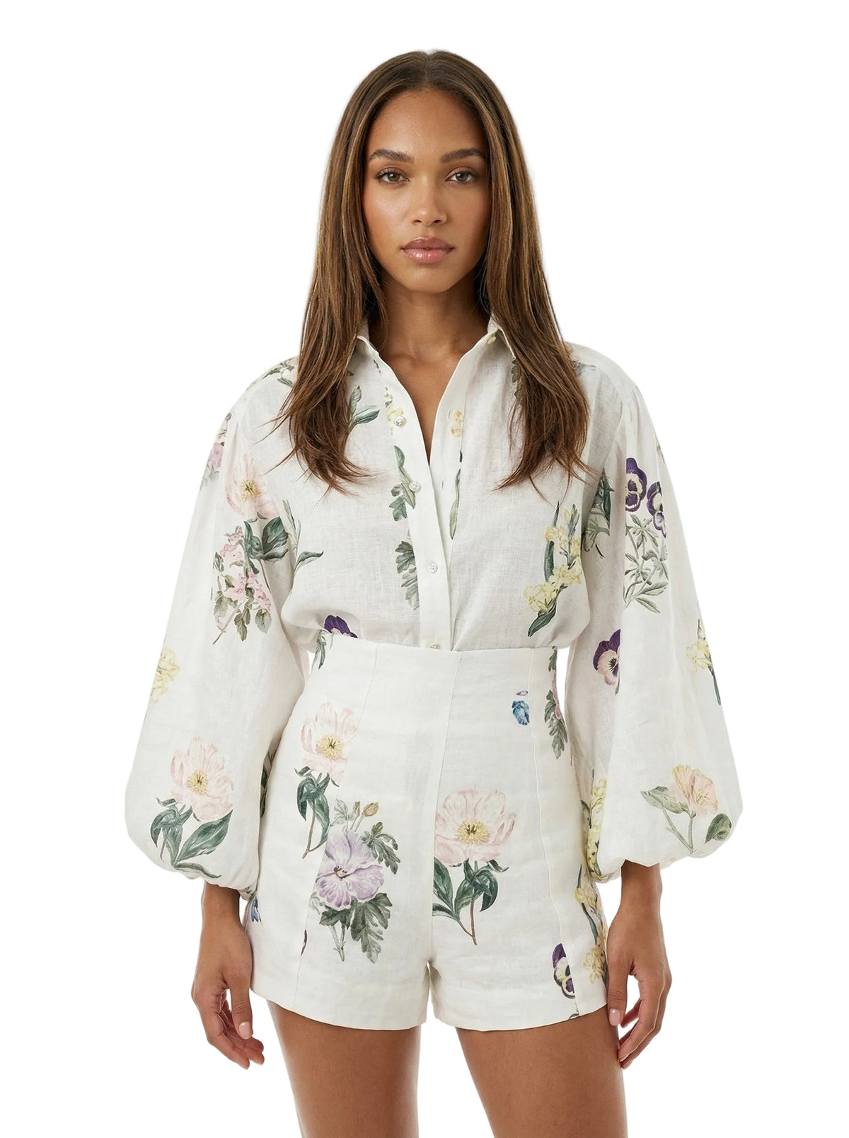 A woman modeling a white linen romper with a colorful floral print, featuring balloon sleeves and a button-up front, against a plain white background.