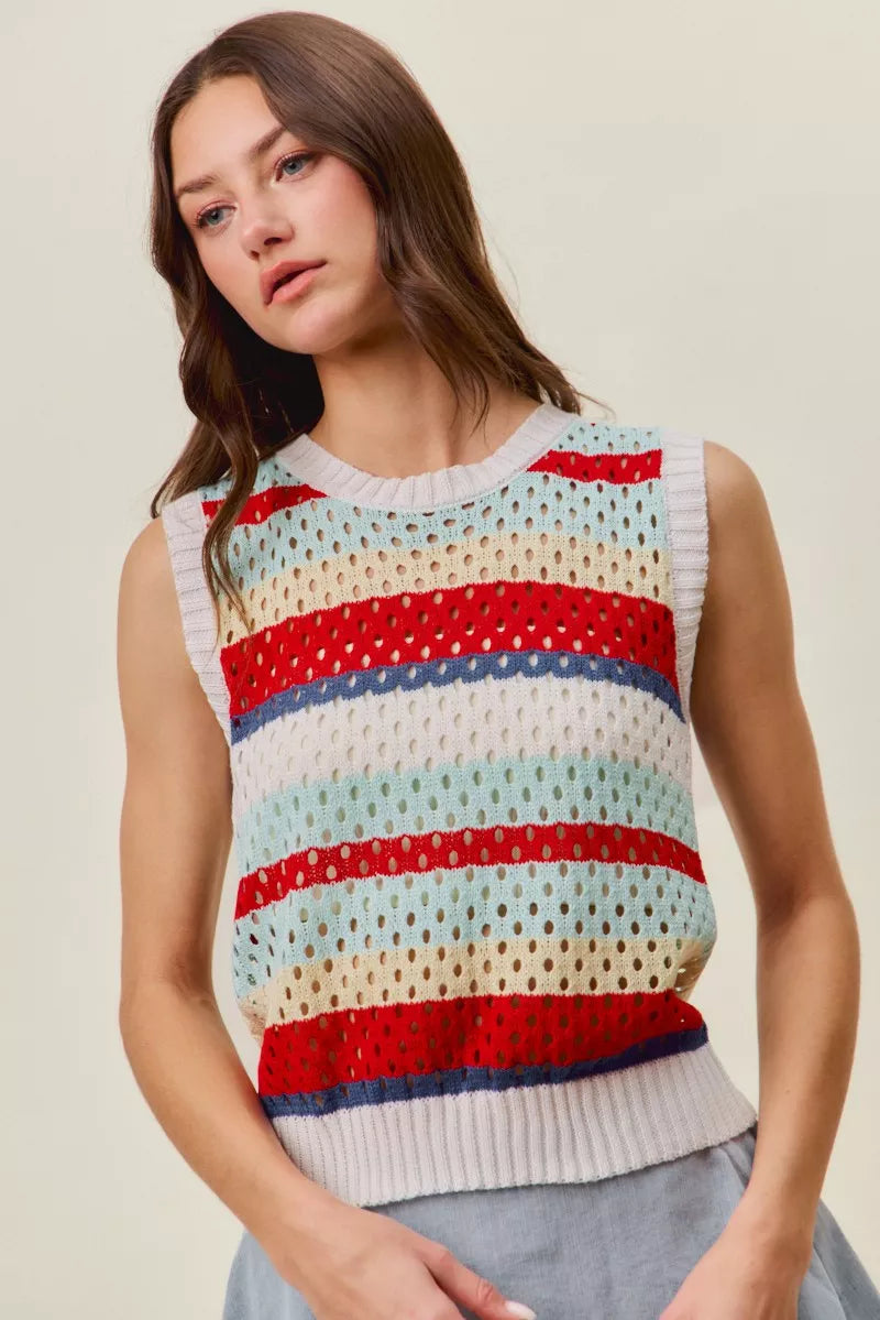 Woman wearing a colorful sleeveless sweater with a neutral background