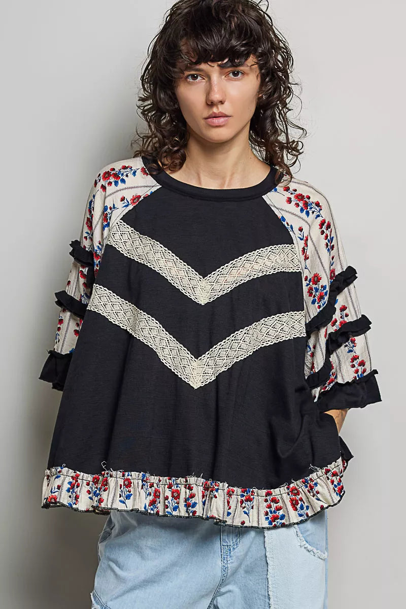 Woman wearing a black and floral patterned top with a plain background