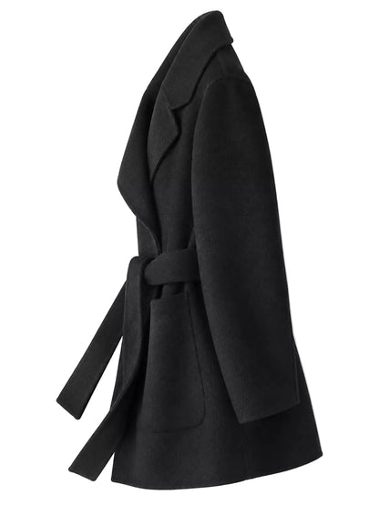 A black belted coat with wide lapels and front patch pockets, shown from a side profile view against a plain white background.