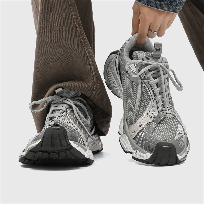 Gray athletic shoes being worn with a neutral background