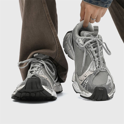 Gray athletic shoes being worn with a neutral background