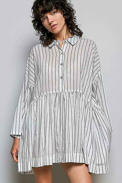 Woman wearing a striped shirt dress against a gray background