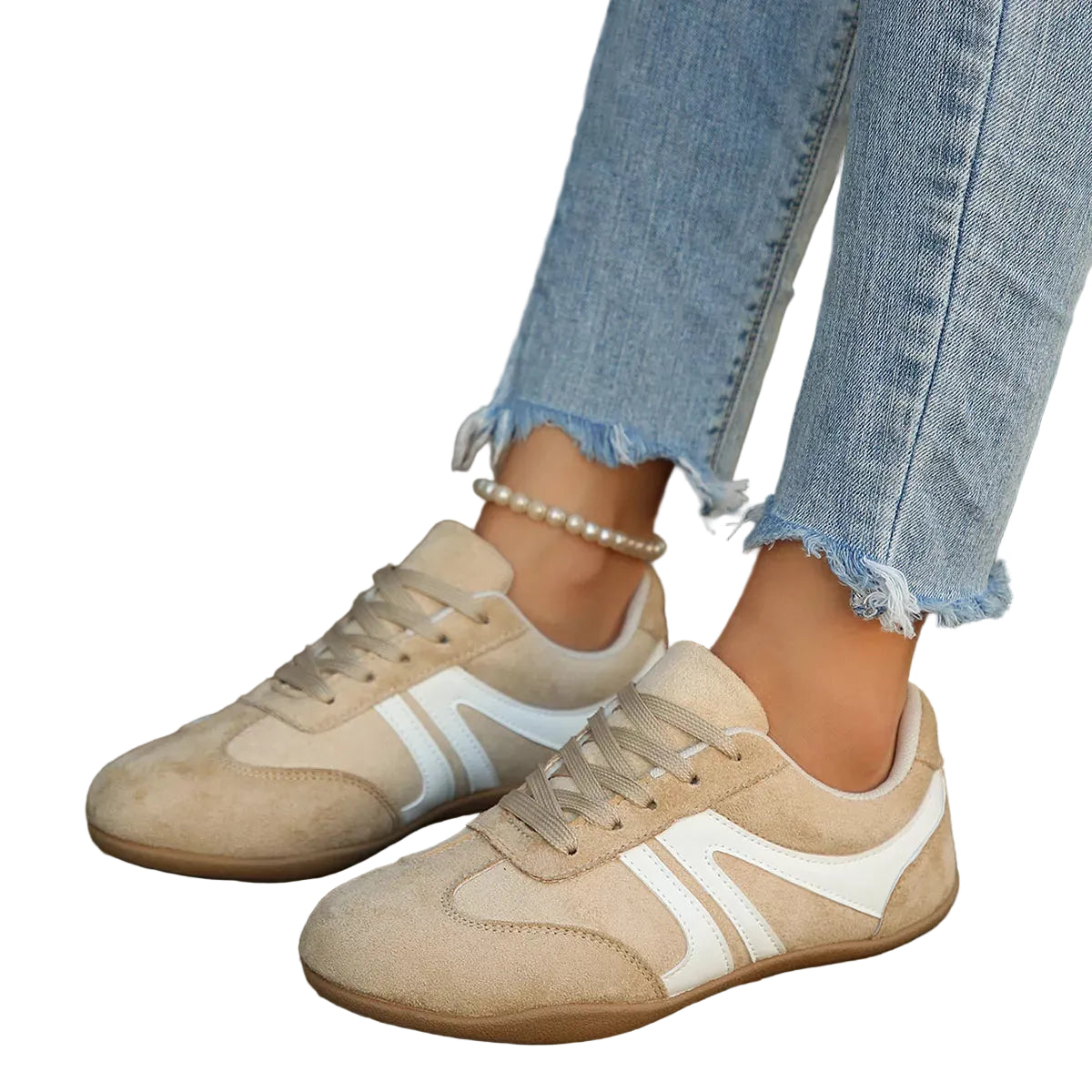 A person wearing beige suede sneakers with white side stripes and light blue frayed-hem jeans, standing on a wooden deck.