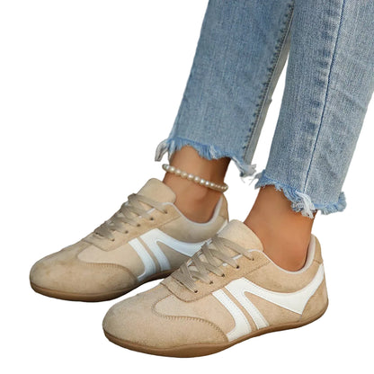 A person wearing beige suede sneakers with white side stripes and light blue frayed-hem jeans, standing on a wooden deck.