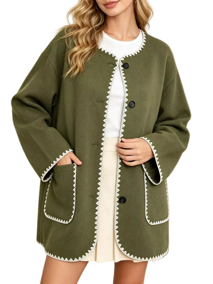 A woman wearing an olive green button-front cardigan with white scalloped trim, layered over a white top and cream skirt, in a bright indoor setting.