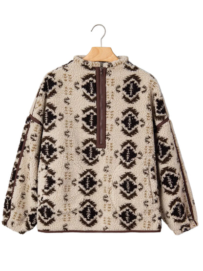 A fleece pullover sweater with a brown and beige geometric pattern, featuring a half-zip closure at the neck, hanging on a wooden hanger against a light gray background.