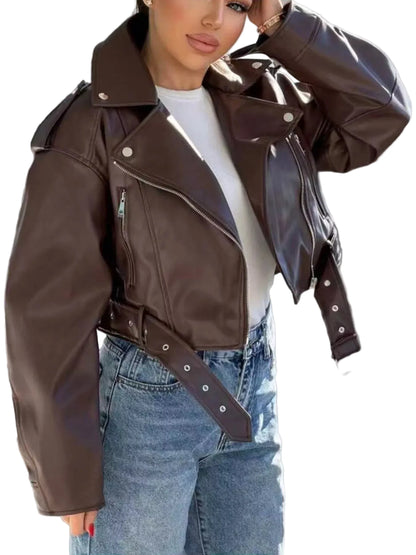 A woman wearing a dark brown faux-leather moto jacket with a matching belt, styled over a white t-shirt and blue jeans.