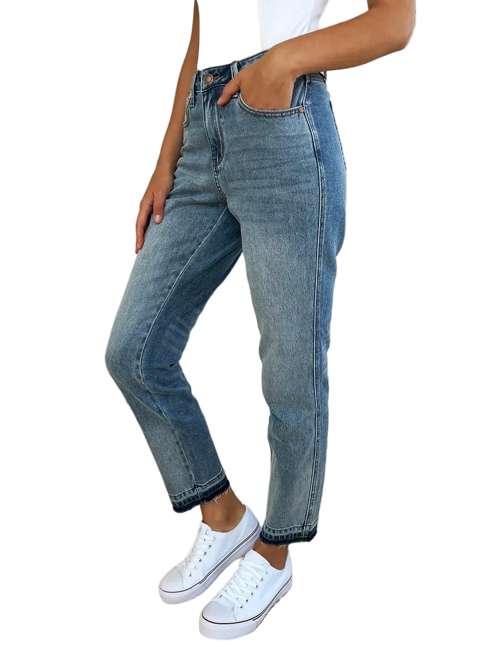 A person wearing light-wash blue denim jeans with a straight-to-regular leg fit, paired with a white top and white sneakers, standing in a modern living room setting.