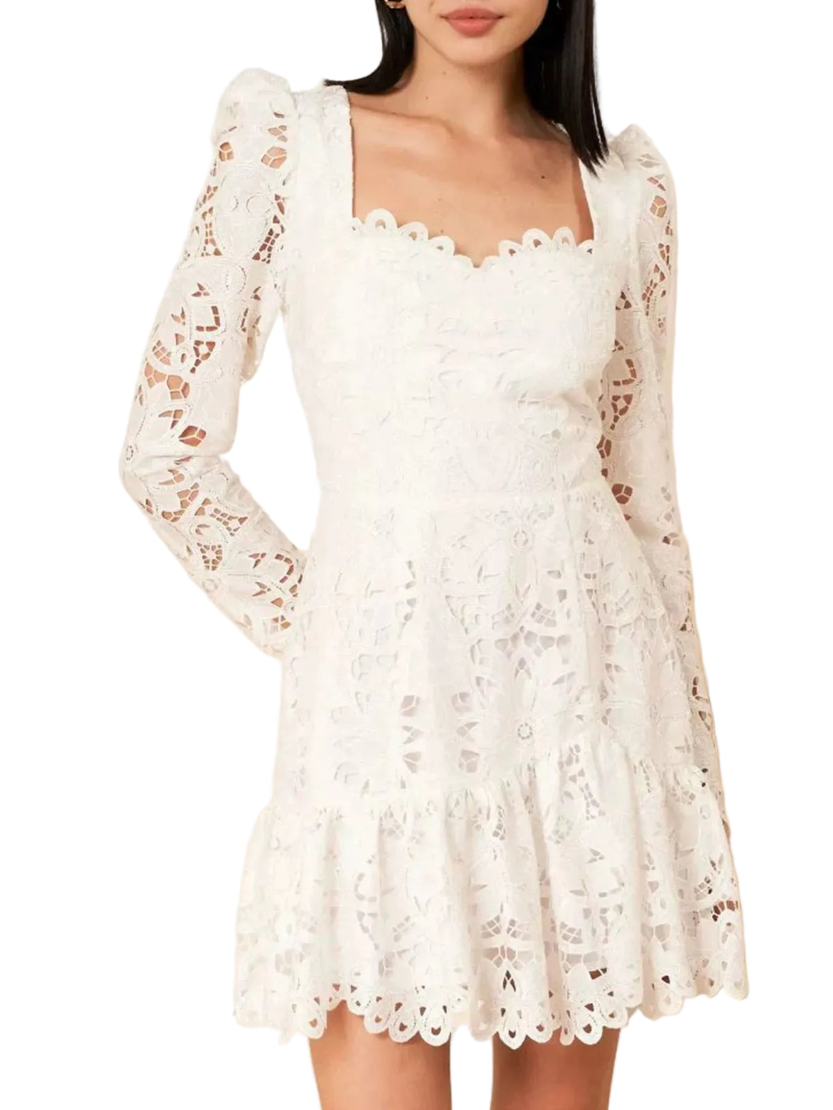 A woman wearing a white eyelet lace mini dress with long puff sleeves, a square neckline, and a flared skirt, photographed indoors against a light cream paneled wall.