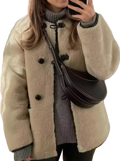 A person wearing a cream-colored sherpa fleece jacket with black buttons, a gray ribbed turtleneck sweater, and carrying a dark brown crescent-shaped shoulder bag.