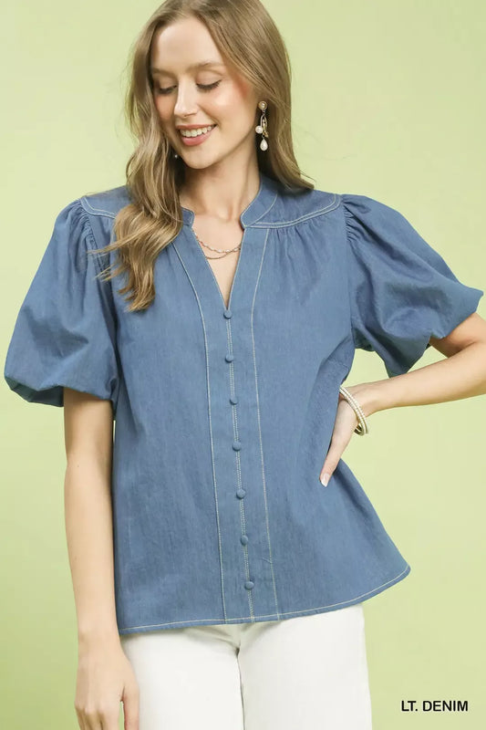 Woman wearing a light denim blouse against a light green background