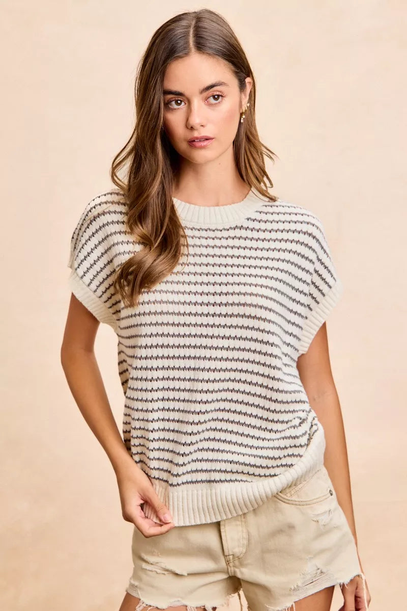 Woman wearing a striped sweater and shorts against a beige background