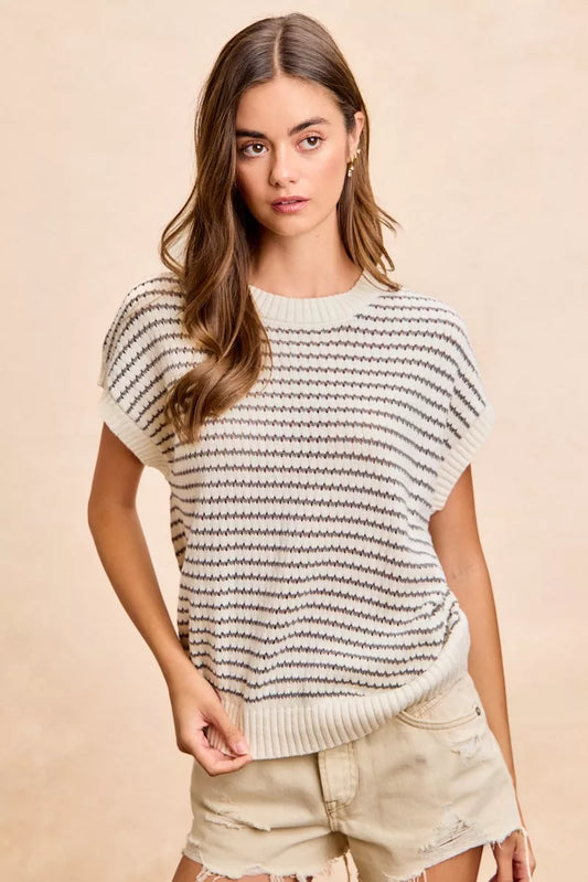 Woman wearing a striped sweater and shorts against a beige background