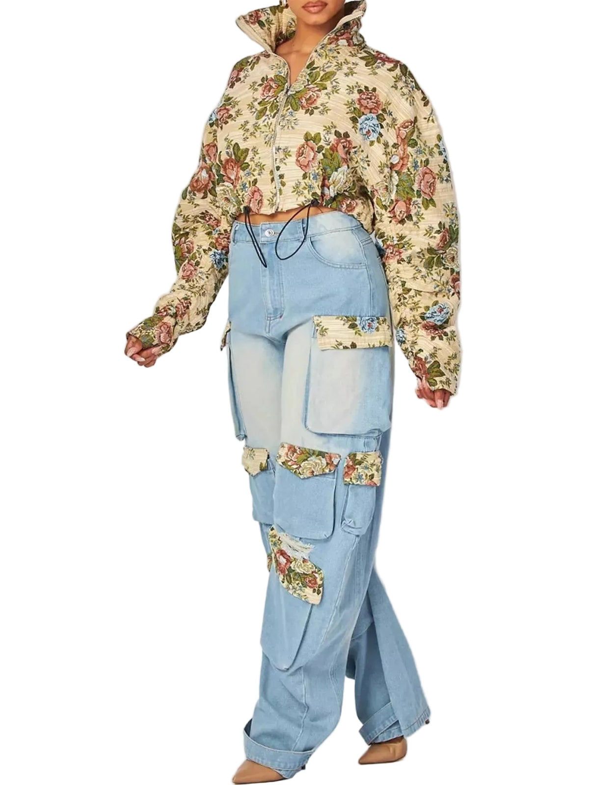 A model wearing a cropped, long-sleeve floral print jacket with a high collar and light-wash blue cargo-style jeans featuring floral patch details on the pockets, set against a plain light gray studio background.