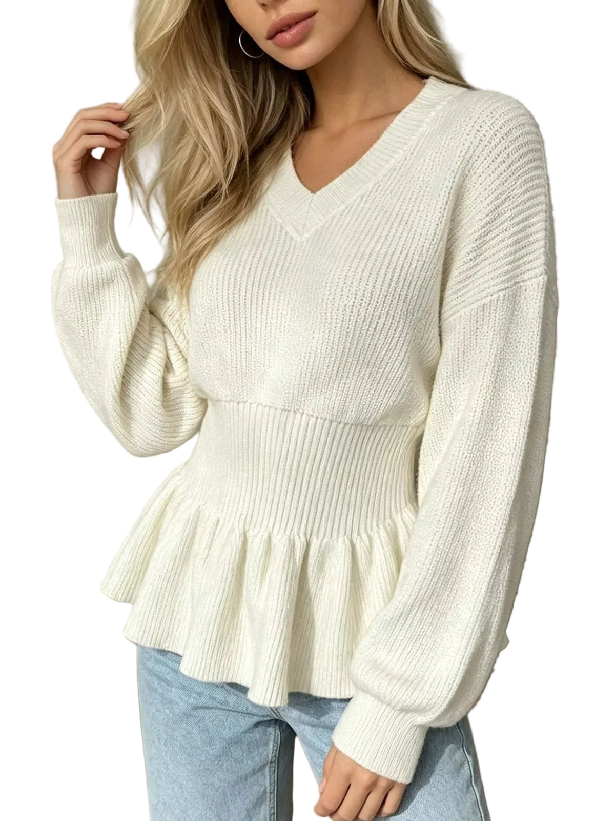 A woman wearing a cream-colored ribbed knit sweater with a V-neck, long sleeves, and a peplum hem, paired with light blue jeans.