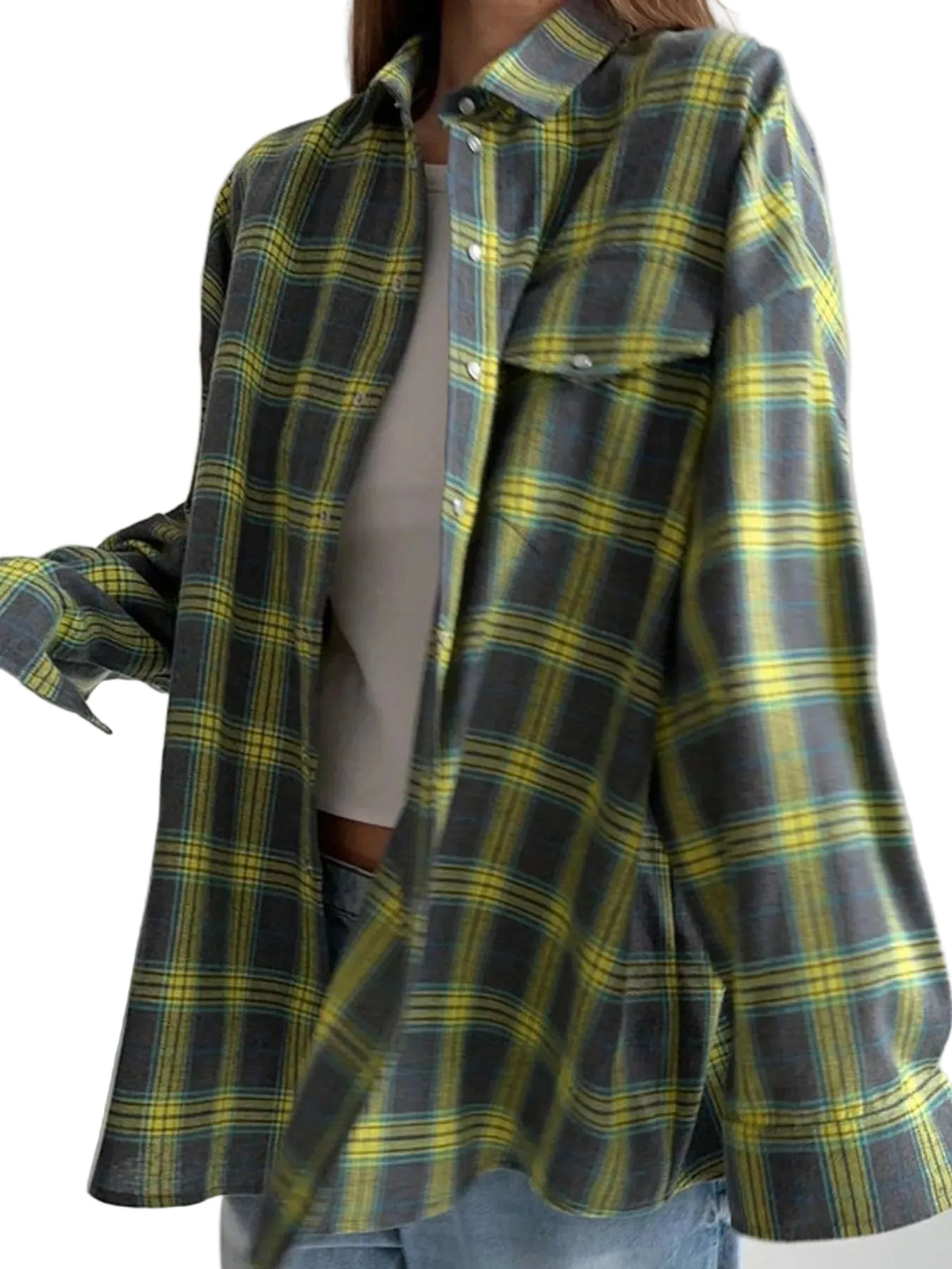 A woman wearing an oversized long-sleeve plaid button-up shirt in dark gray, yellow, and green, layered over a white top and blue jeans.