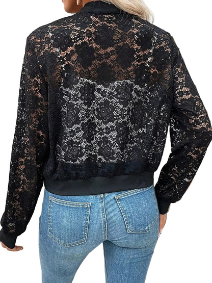 A woman viewed from the back wearing a black lace bomber jacket with floral lace panels and ribbed collar, cuffs, and hem, paired with blue jeans in an outdoor patio setting.